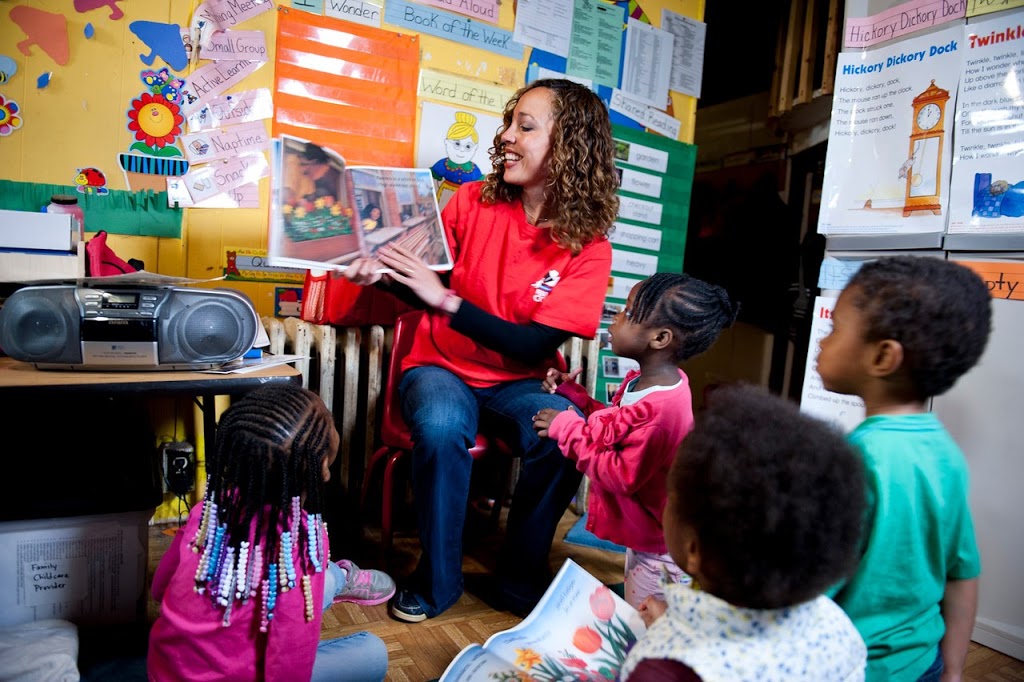 Female Reading Corps tutor reading a picture book to 4 young children