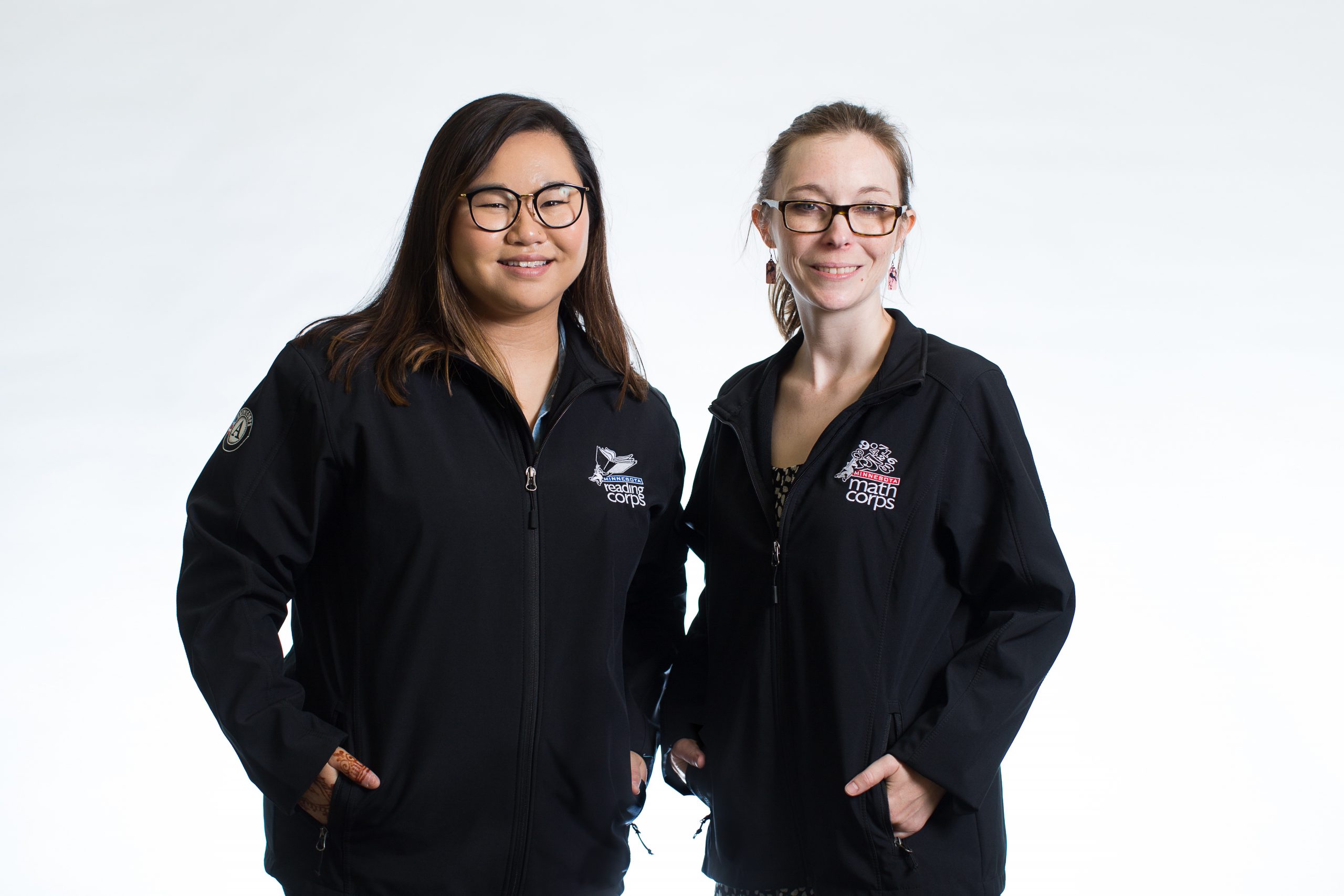 Two females modeling black Reading Corps and Math Corps jackets
