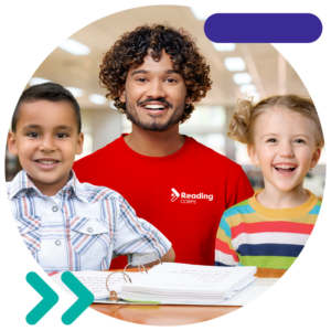 Reading Corps tutor smiling with two students in a reading tutoring intervention.